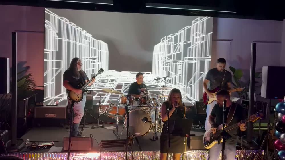 The Pollies on stage in front of a bright graphic backdrop